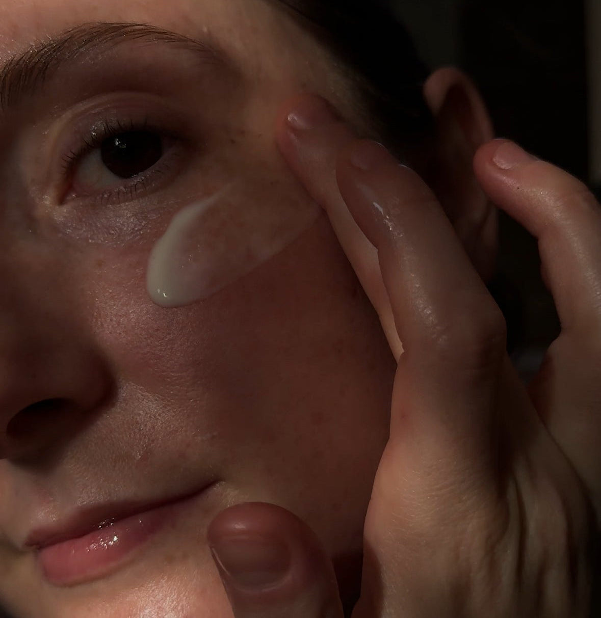 Person applying cream to their face with a close-up view.